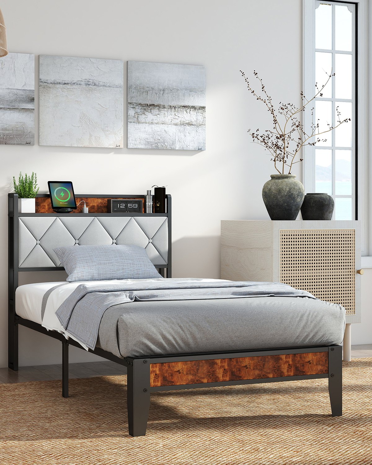 A metal bed frame with a soft-padded headboard, made up with grey bedding in a bright room.